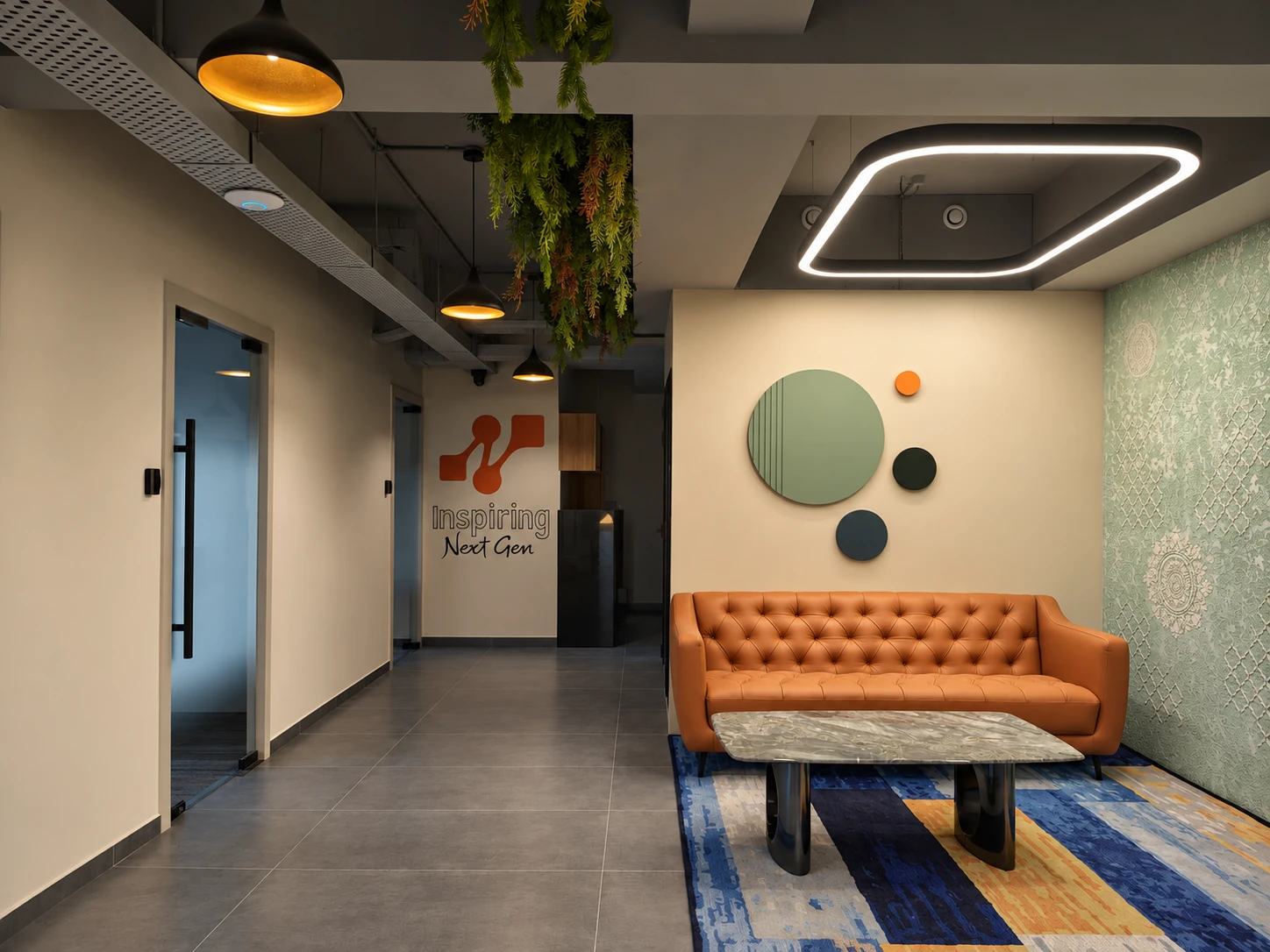 Bitpod lounge with an orange sofa, sage wall decorations and a blue and orange rug