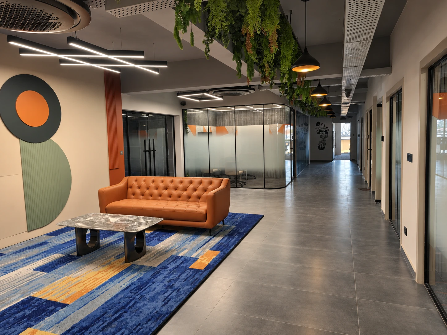 Bitpod Alake lounge with orange sofas, hanging greenery and glass meeting rooms